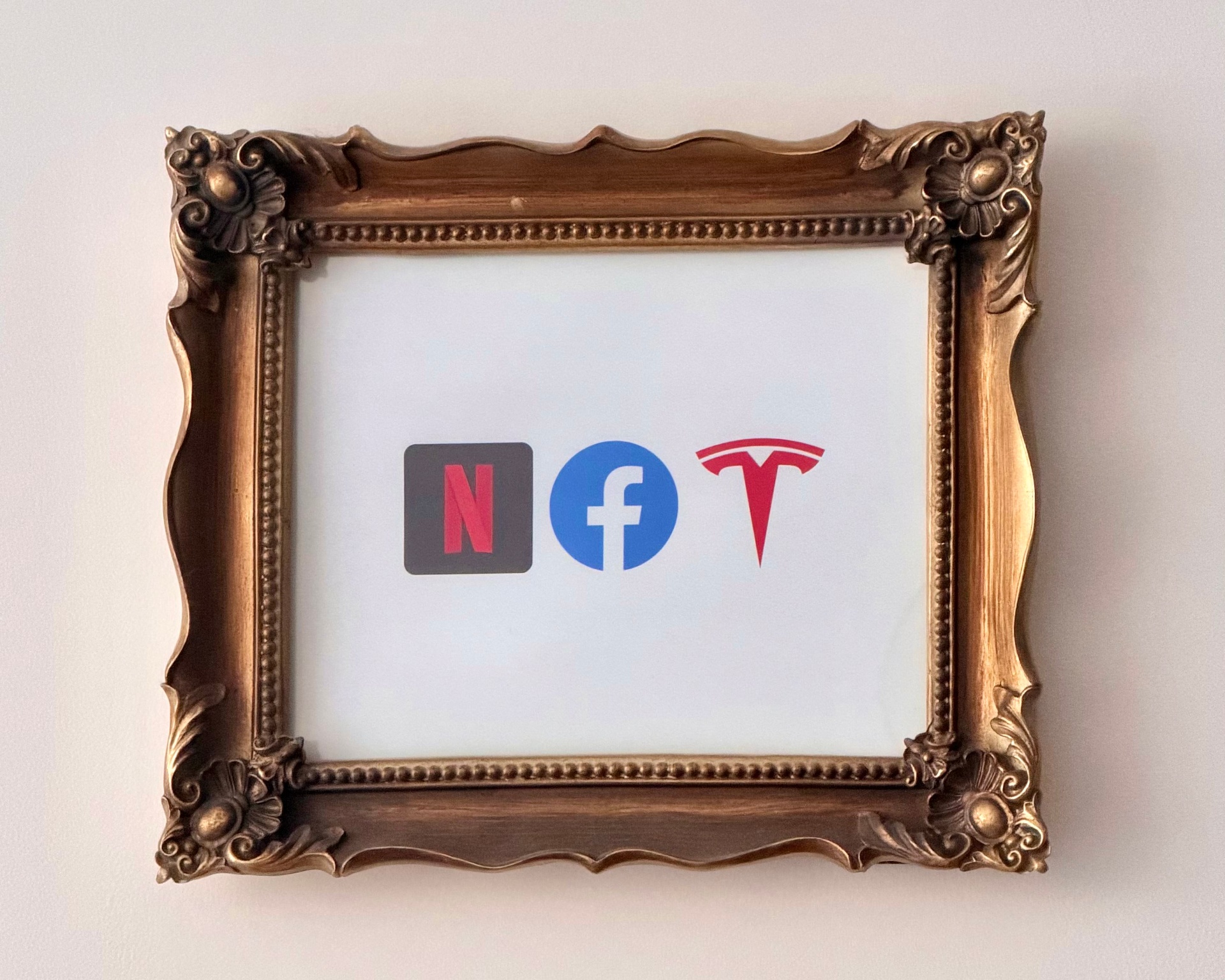 Ornate gold frame containing Netflix, Facebook, and Tesla logos.
